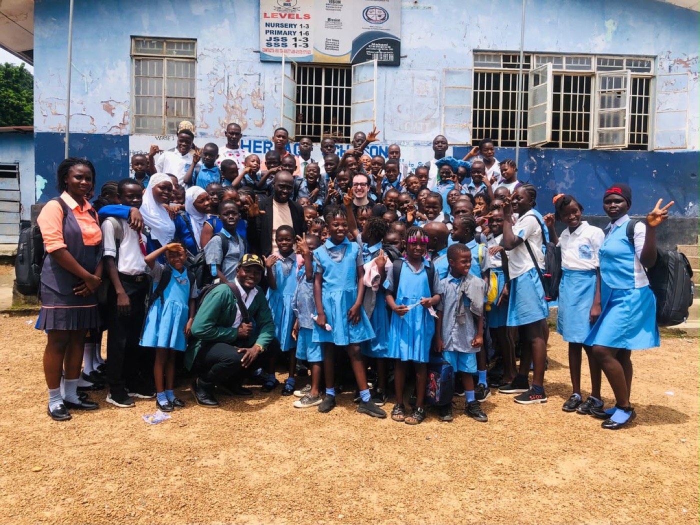 Max Brie with students and staff outside Heritage Preparatory High School in Makeni, Sierra Leone